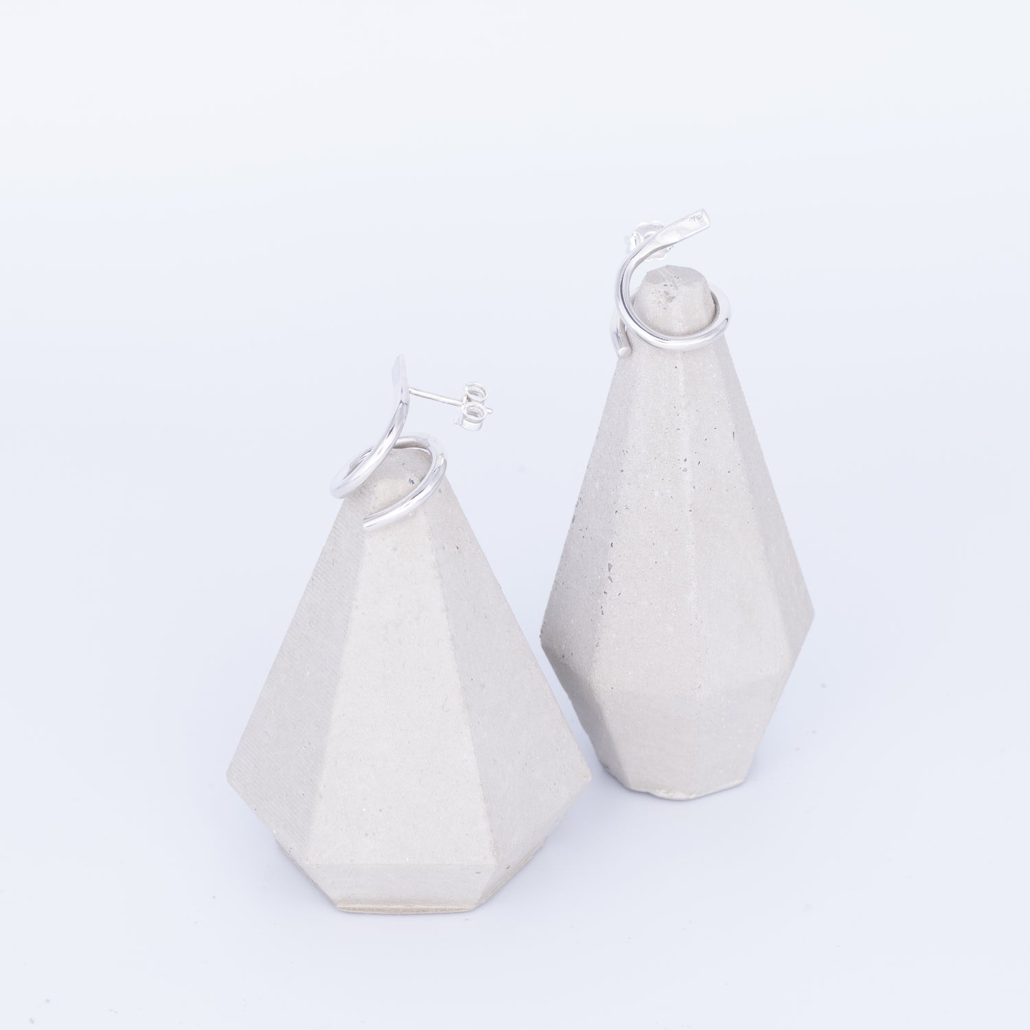 White geometric earrings on a light gray background