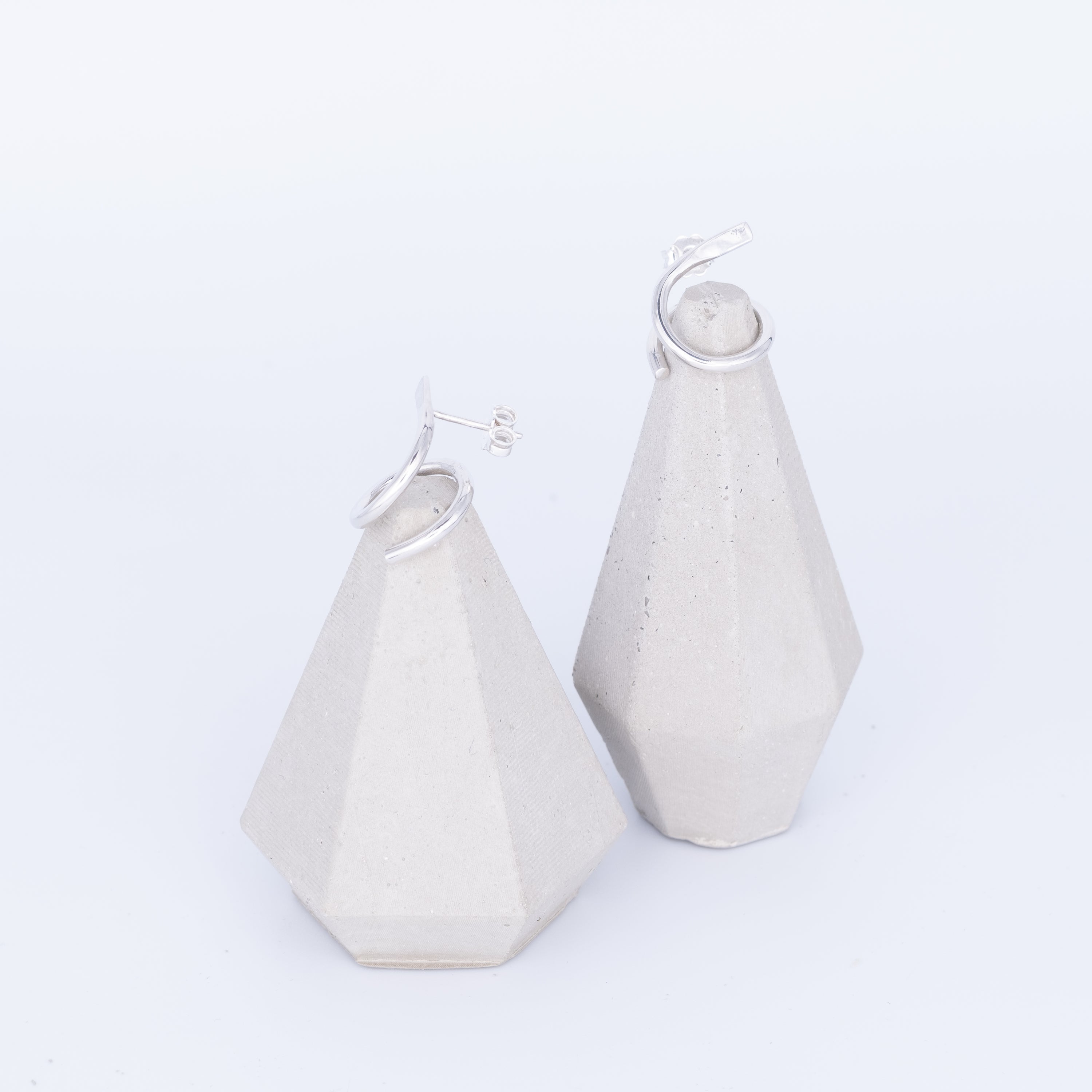 White geometric earrings on a light gray background