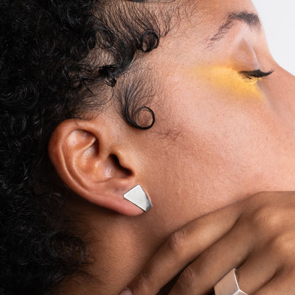Close-up of a woman wearing a silver earring with a neutral background