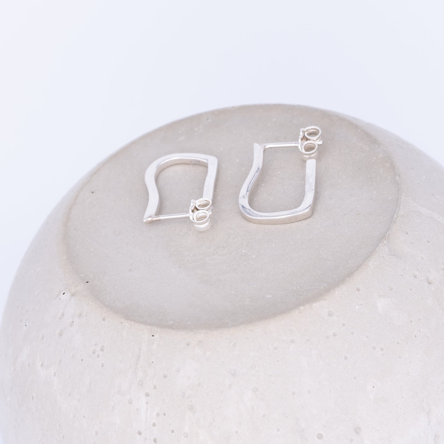 Pair of silver hoop earrings on a light stone surface