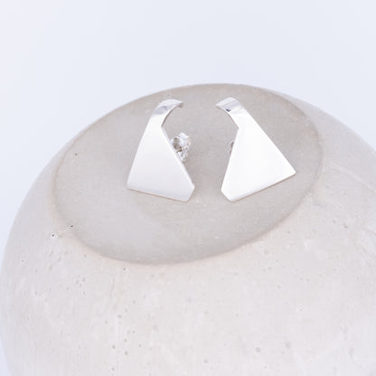 Pair of silver triangle earrings on a textured white surface