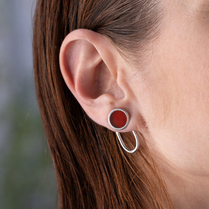 Close-up of an ear wearing a silver earring with acarnelian gemstone.