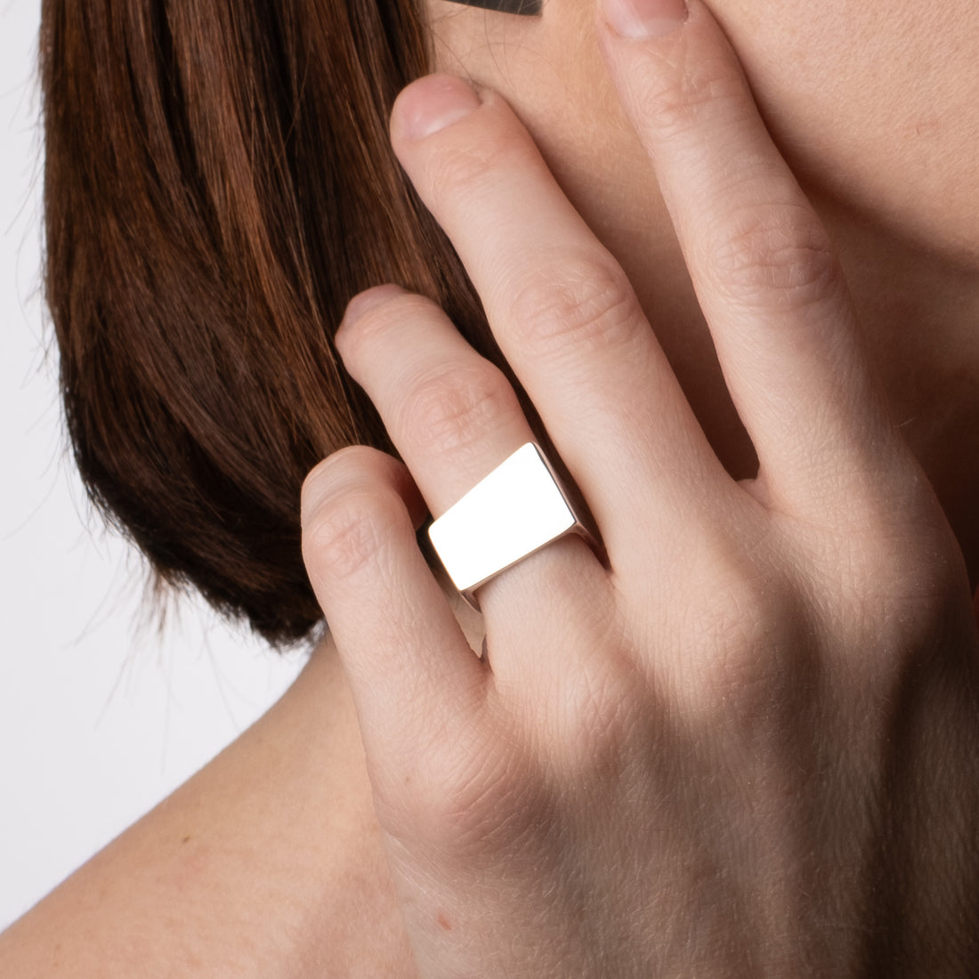 Hand wearing a silver ring with a plain background