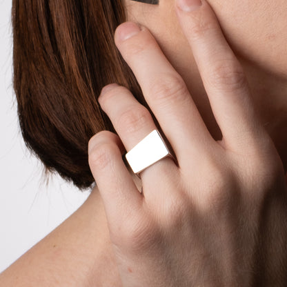 Hand wearing a silver ring with a plain background