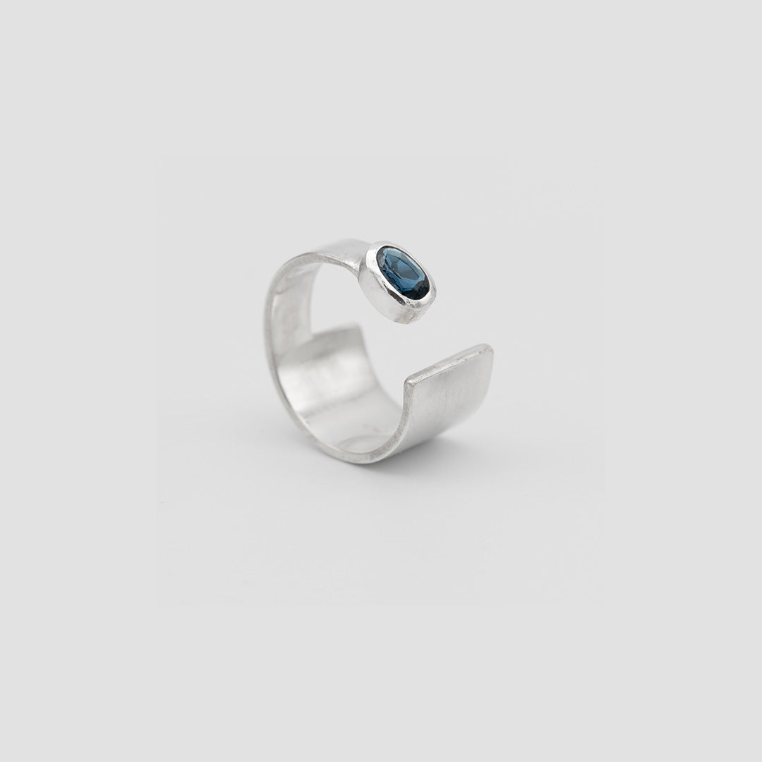 Silver ring with a blue gemstone on a light gray background london blue topaz