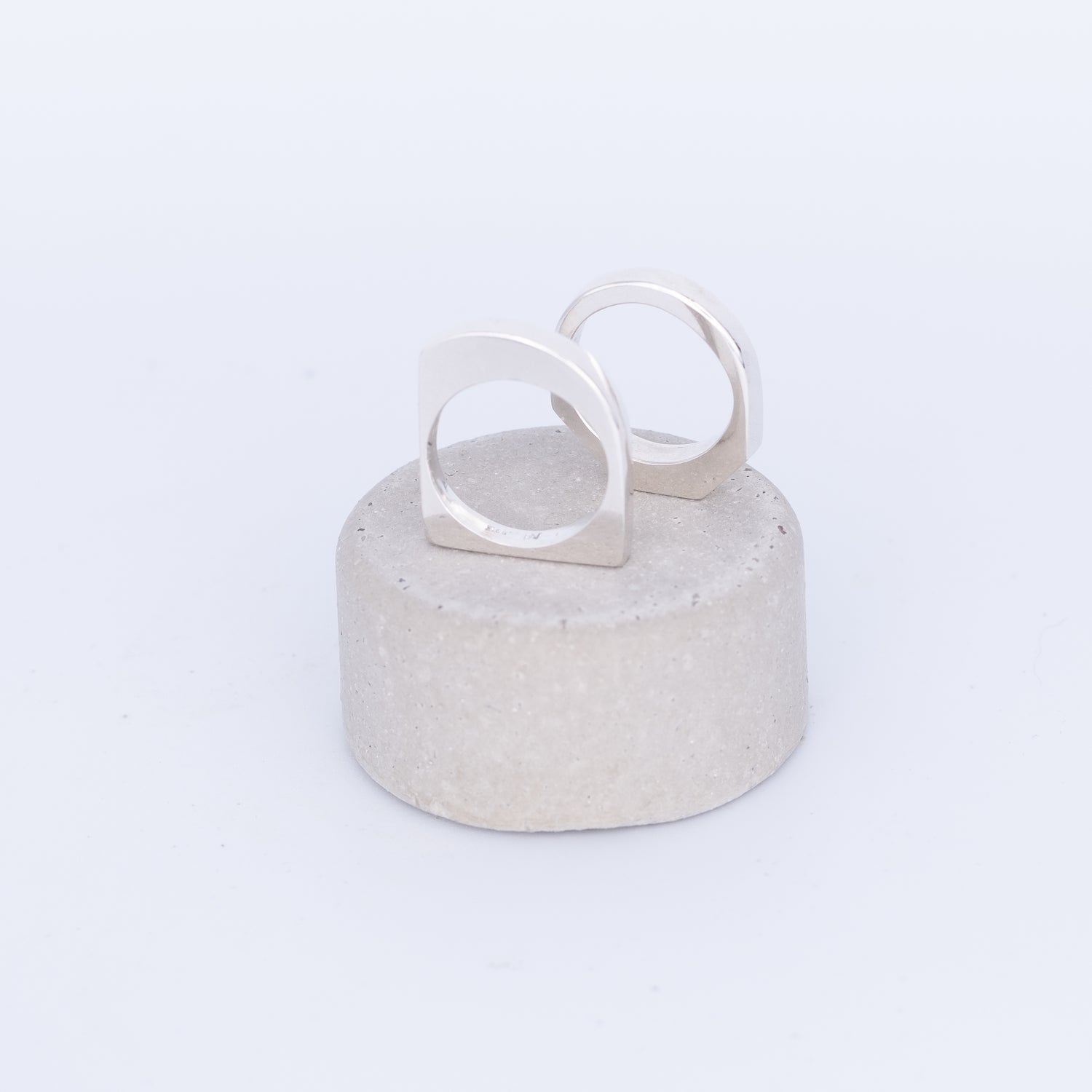 Silver ring on a textured gray stand against a white background