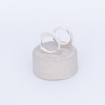 Silver ring on a textured gray stand against a white background