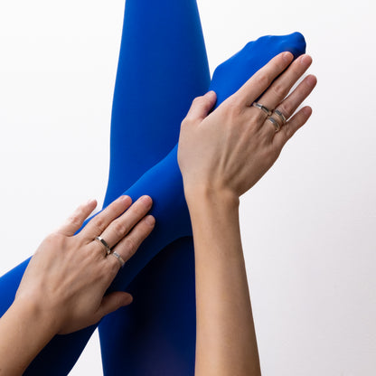 Close-up of hands holding blue fabric against a white background
