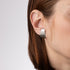 Close-up of a person wearing a silver hoop earring on a plain background