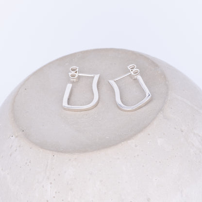 Silver hoop earrings on a round stone surface