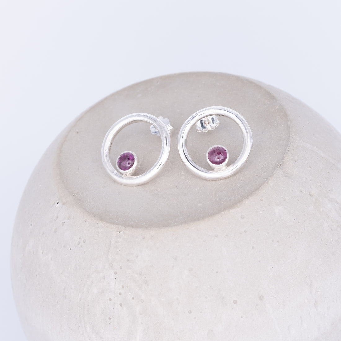 Silver earrings with purple gemstones on a white stone tourmaline