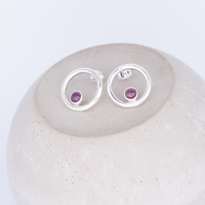 Silver earrings with purple gemstones on a white stone tourmaline