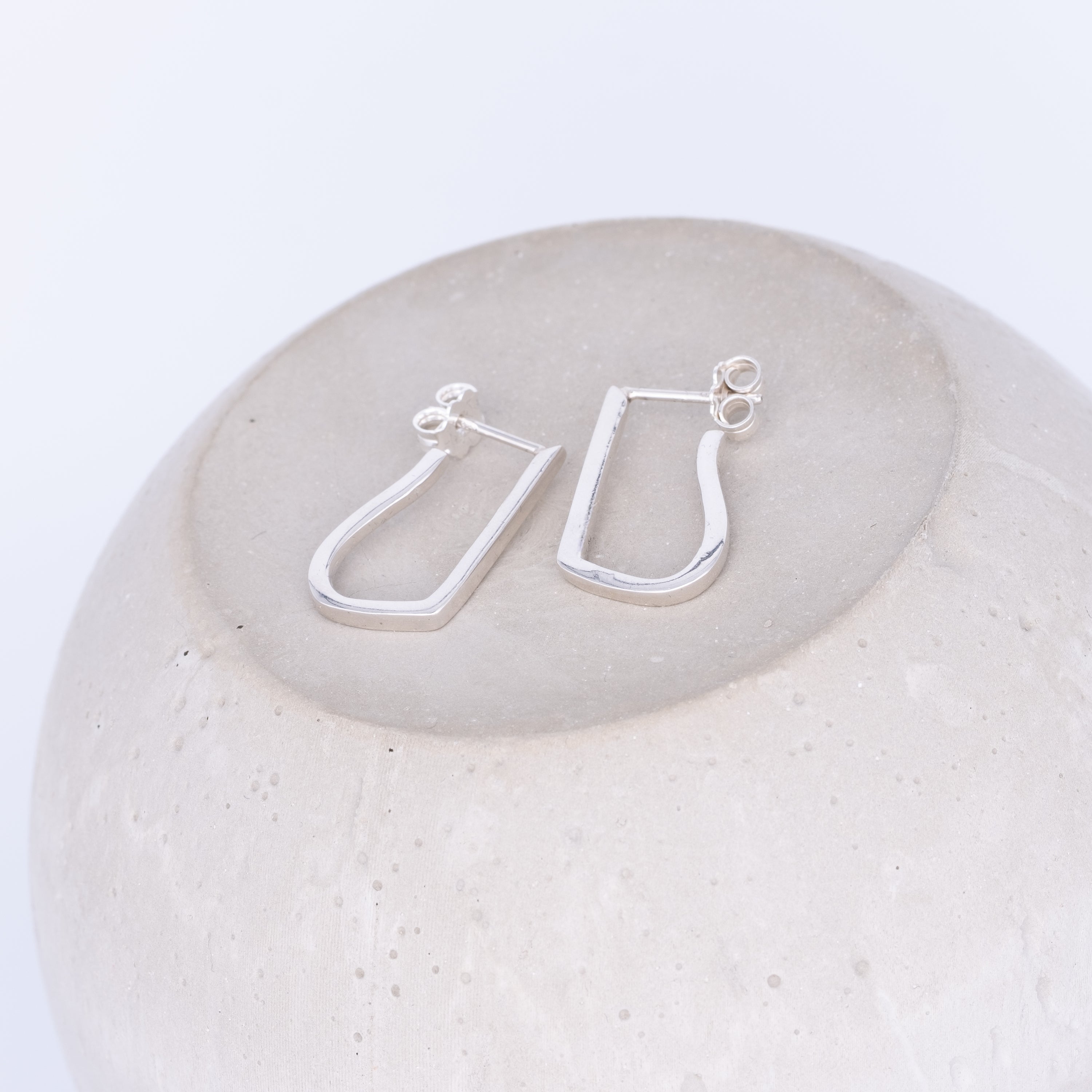Silver hoop earrings on a textured white surface