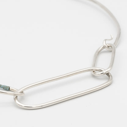 Silver chain necklace on a light gray background
