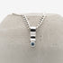 Silver necklace with a blue gemstone pendant on a textured gray surface