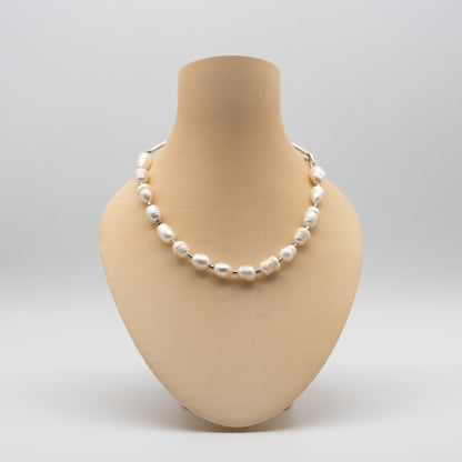 Pearl necklace on a beige mannequin bust against a light gray background