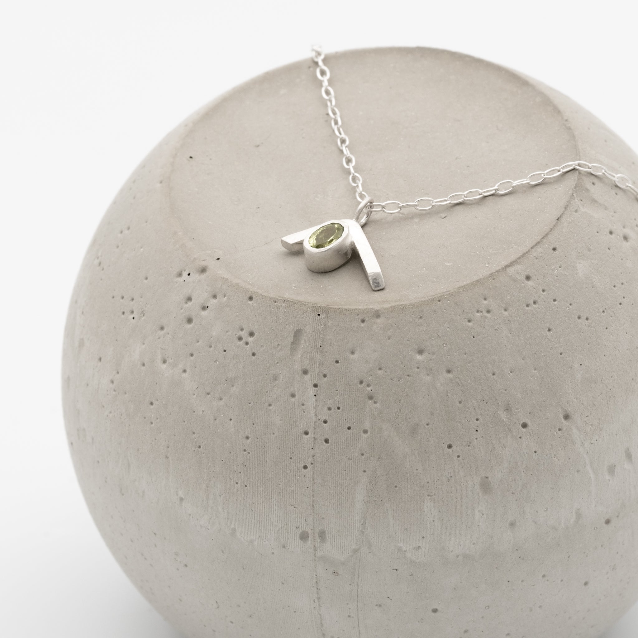 Silver necklace with a pendant on a concrete block