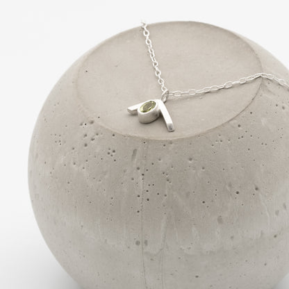 Silver necklace with a pendant on a concrete block