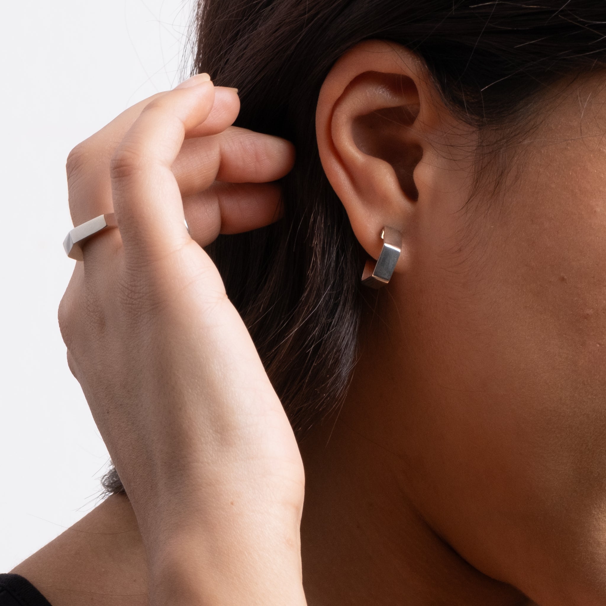 Person wearing a silver earring with a neutral background