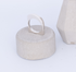 Silver ring on a textured concrete block with another similar block in the background.