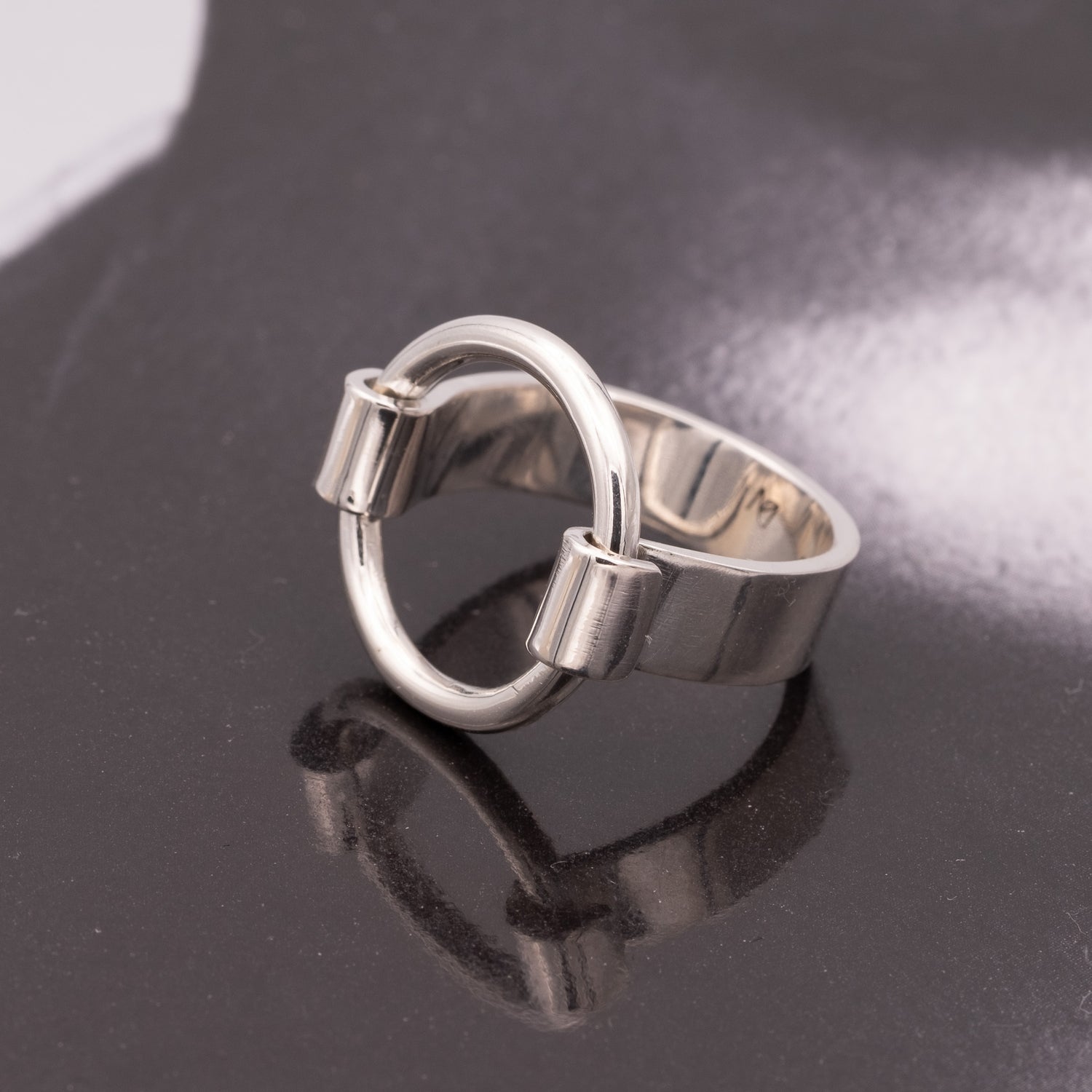 Silver ring with a unique design on a reflective black surface