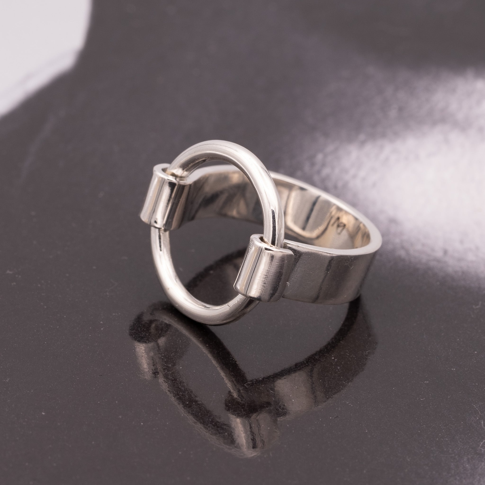 Silver ring with a unique design on a reflective black surface
