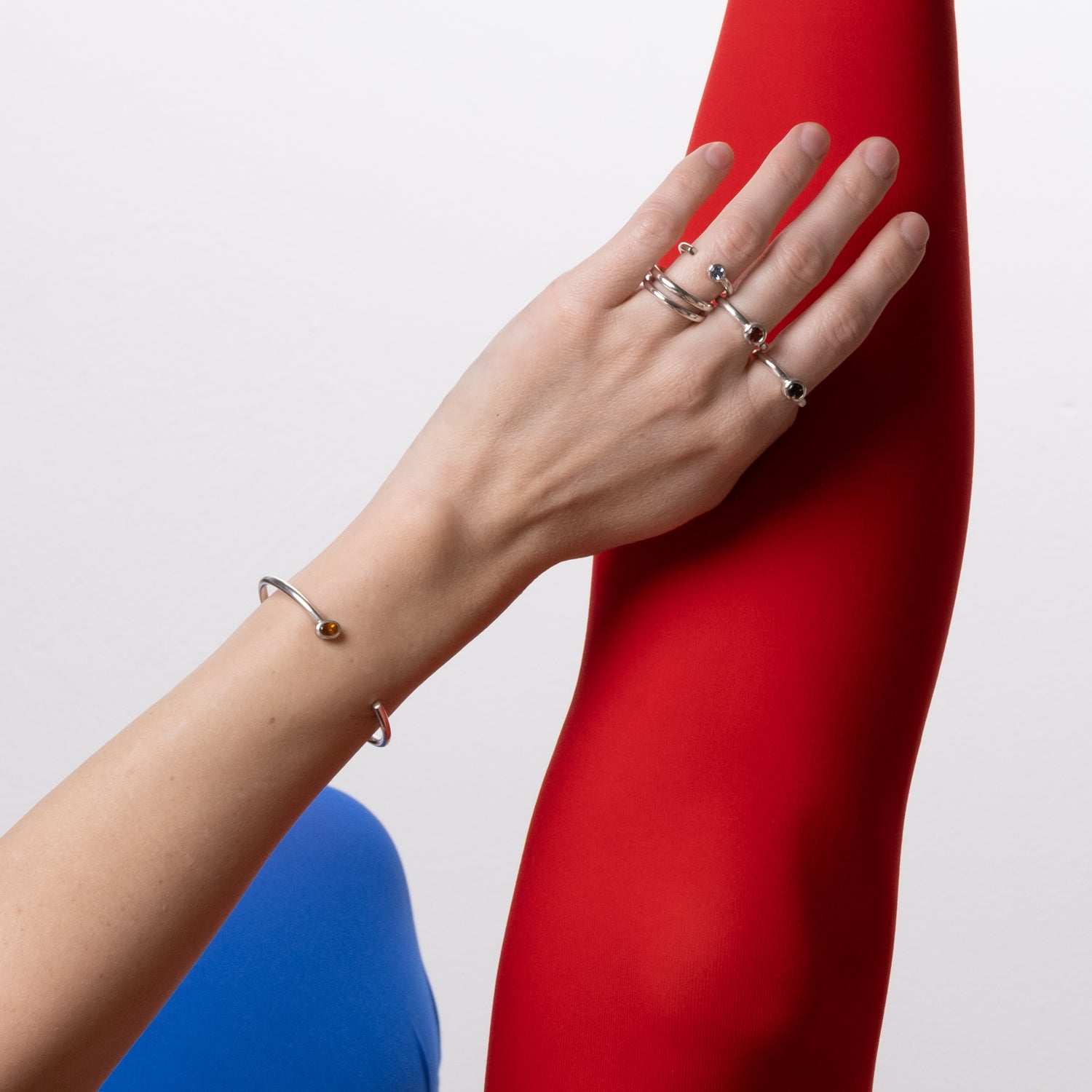 Hand with multiple rings on a red surface