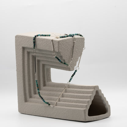 Concrete block with a necklace draped over it on a white background