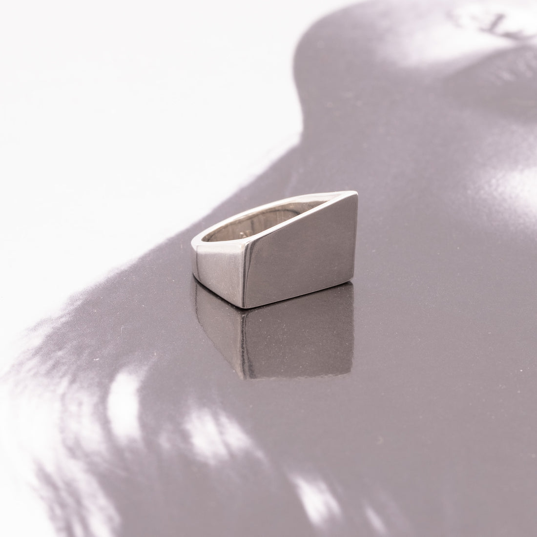 Silver triangular ring on a reflective surface