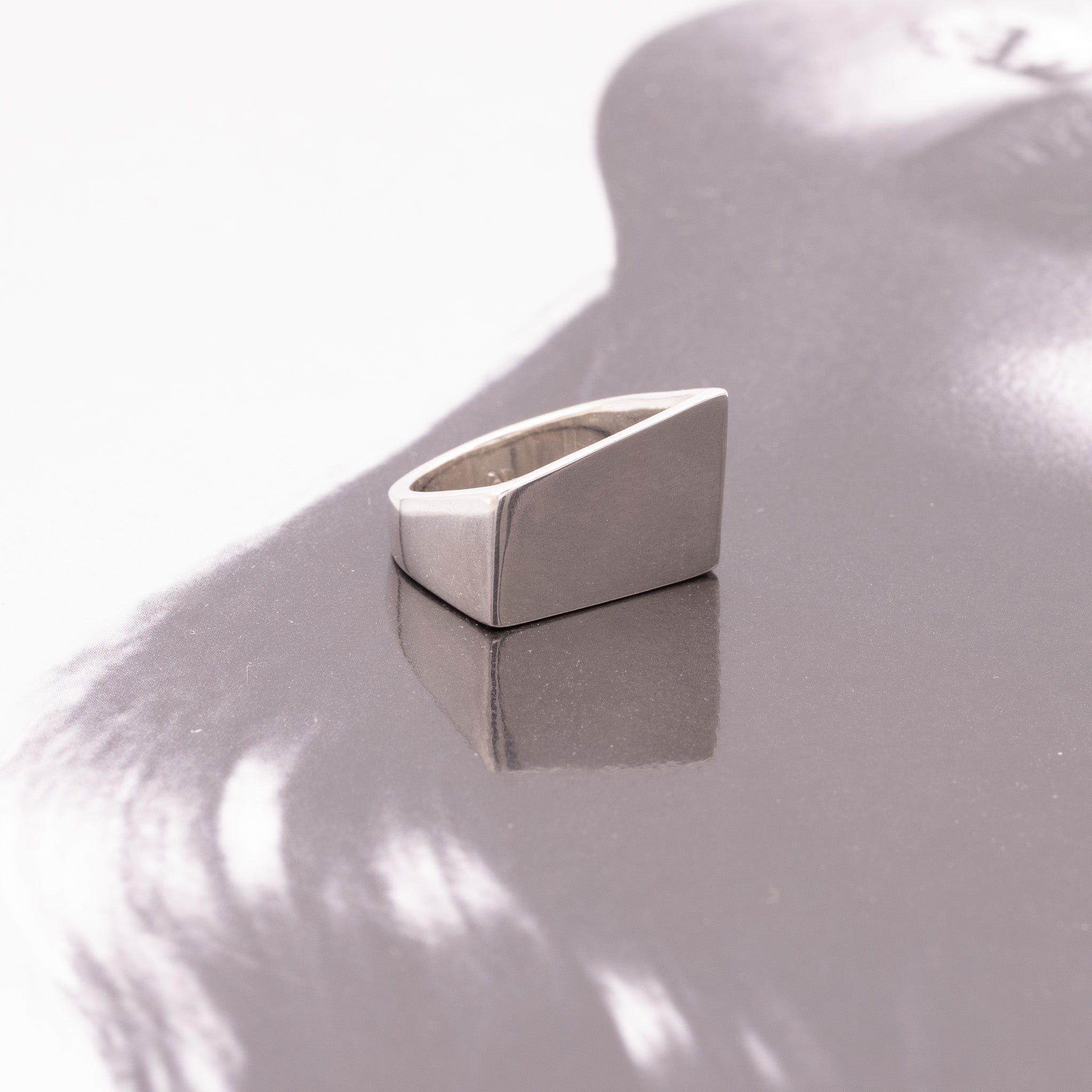 Silver triangular ring on a reflective surface