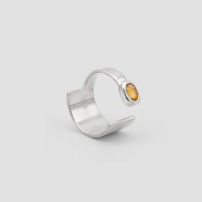 Silver ring with a yellow gemstone on a light gray background