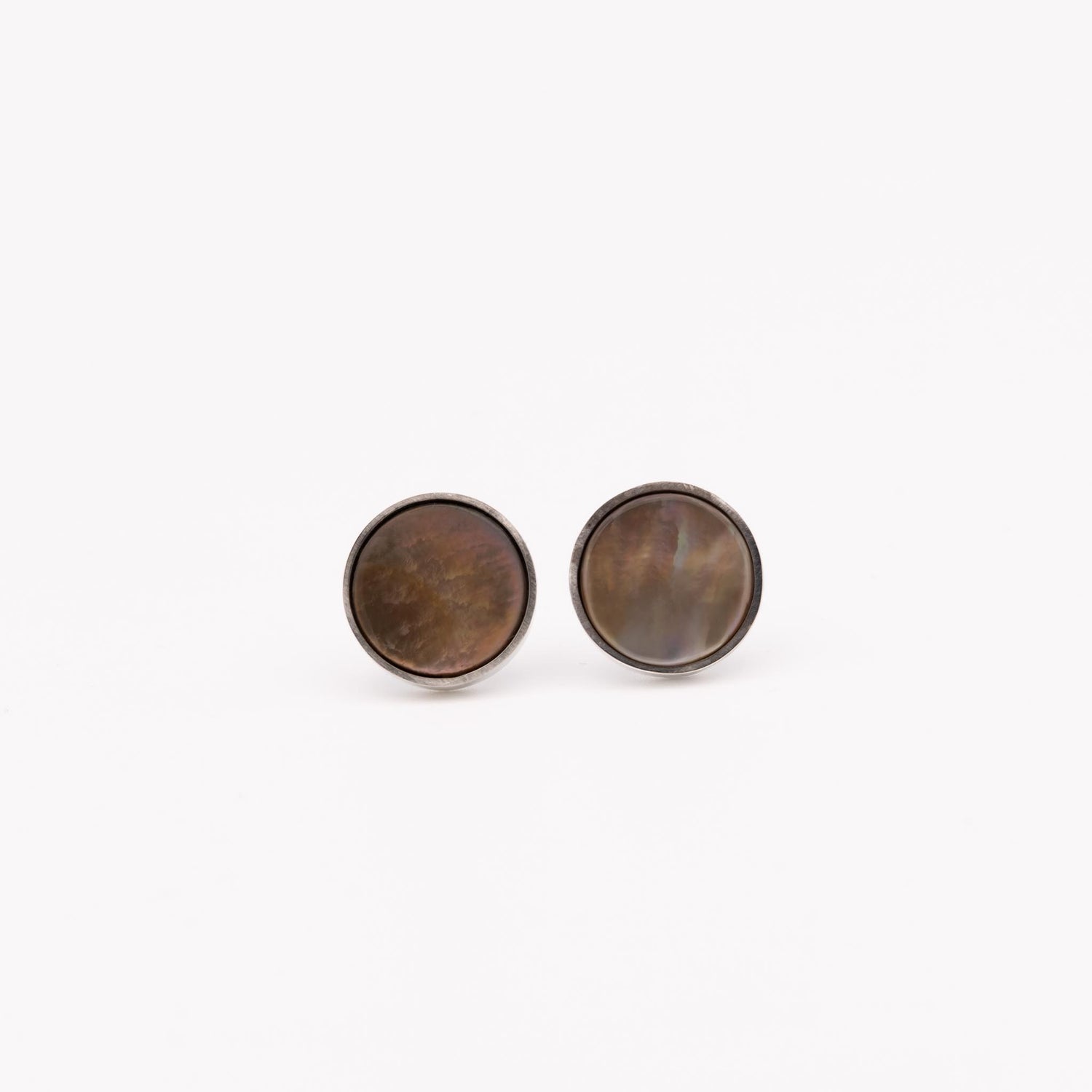 Round earrings with a metallic finish on a white background mother of pearl