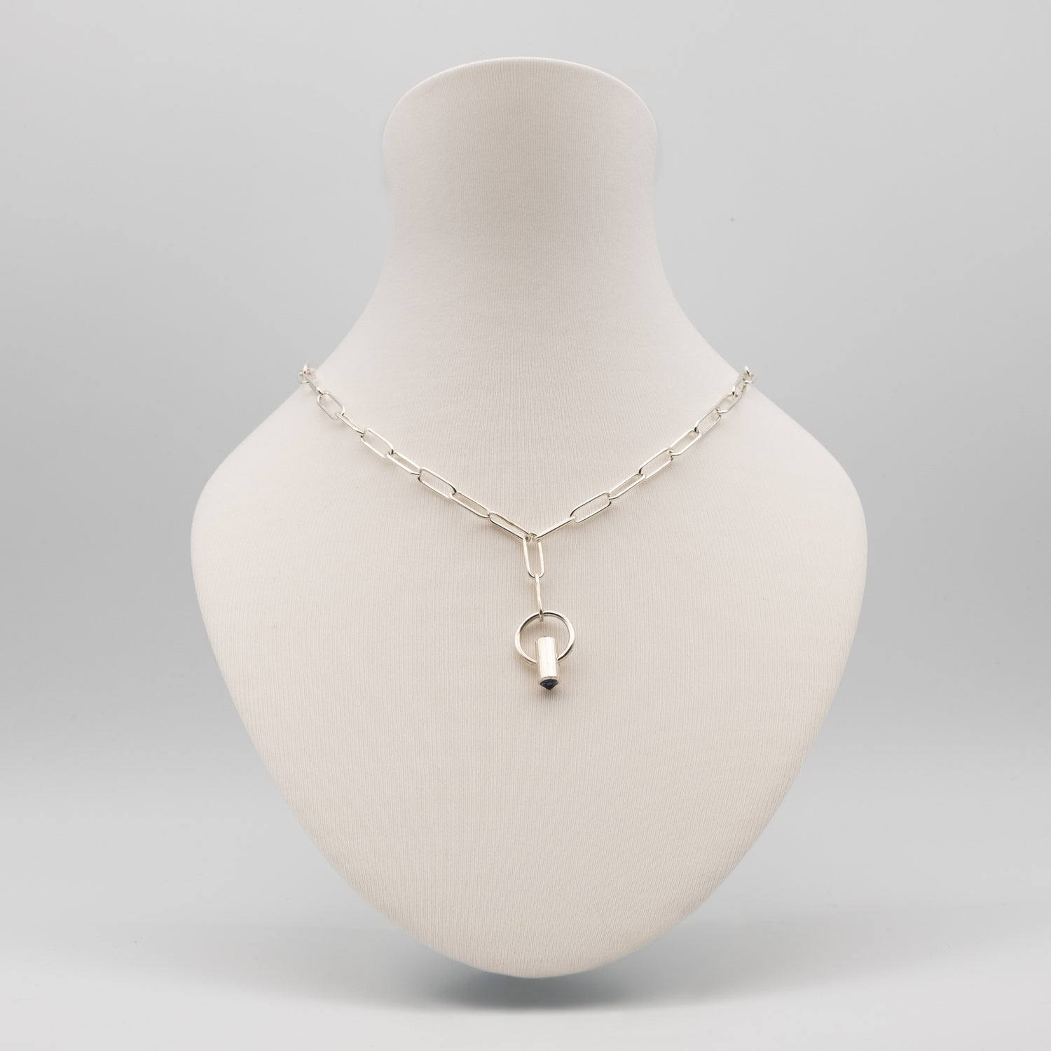 A silver paperclip chain necklace with a Y-shaped connector and a small ring pendant, displayed on a cream-colored mannequin bust against a light gray background.