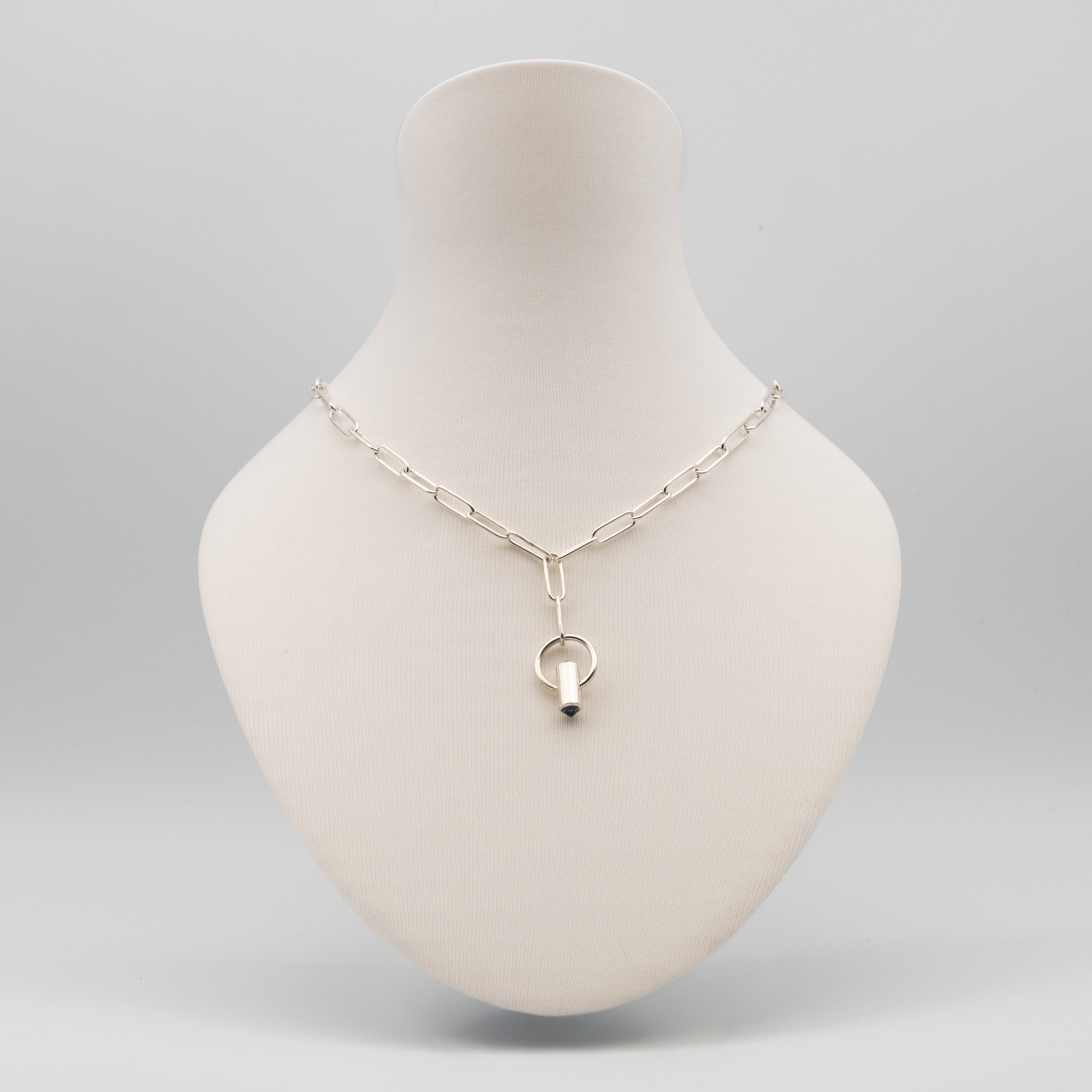 A silver paperclip chain necklace with a Y-shaped connector and a small ring pendant, displayed on a cream-colored mannequin bust against a light gray background.
