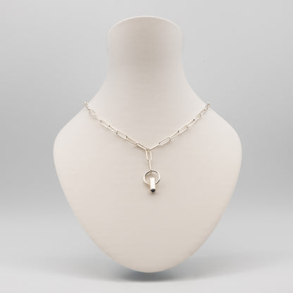 A silver paperclip chain necklace with a Y-shaped connector and a small ring pendant, displayed on a cream-colored mannequin bust against a light gray background.