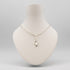 A silver paperclip chain necklace with a Y-shaped connector and a small ring pendant, displayed on a cream-colored mannequin bust against a light gray background.
