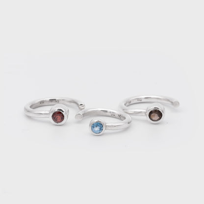 Three silver rings with gemstones on a light gray background