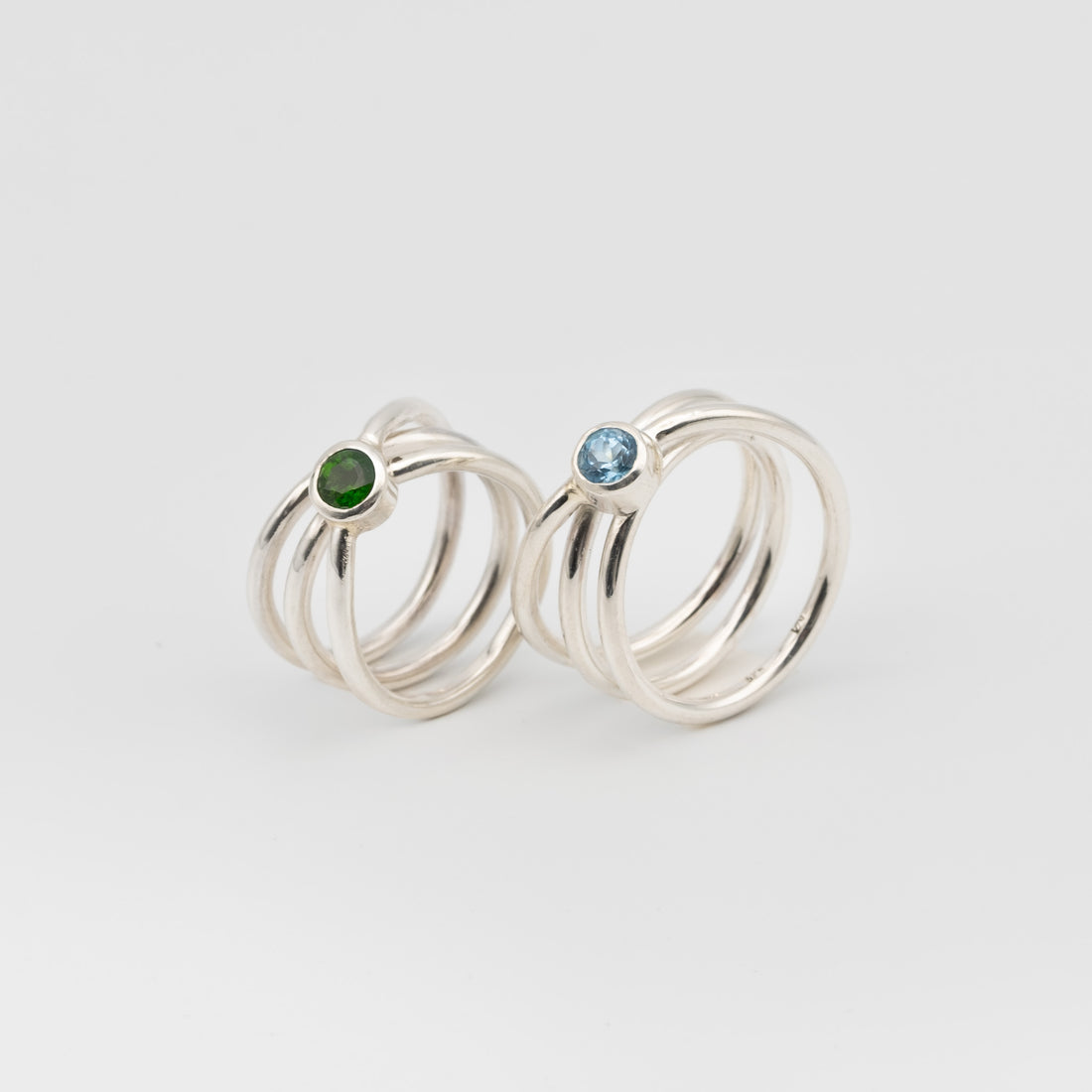 silver handmade rings in a shape of an orbit with a single gemstone set. now single silver wire wrapped and creating coils. 