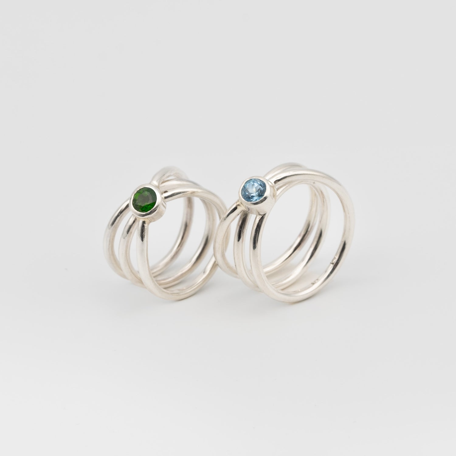 silver handmade rings in a shape of an orbit with a single gemstone set. now single silver wire wrapped and creating coils. 