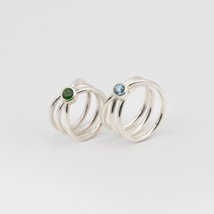 silver handmade rings in a shape of an orbit with a single gemstone set. now single silver wire wrapped and creating coils. 