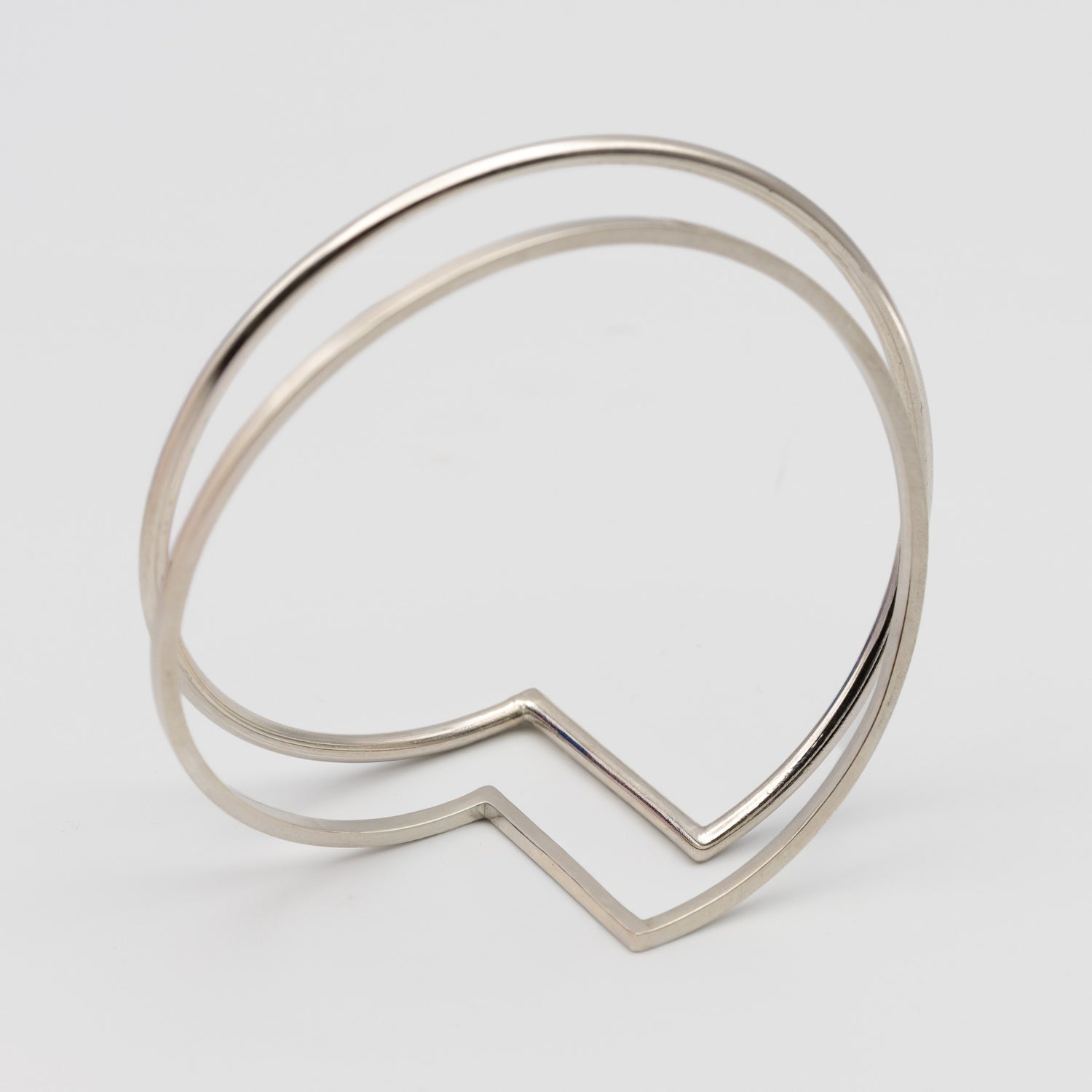 two minimalistic silver bangles one made out of square wire the other out of round wire