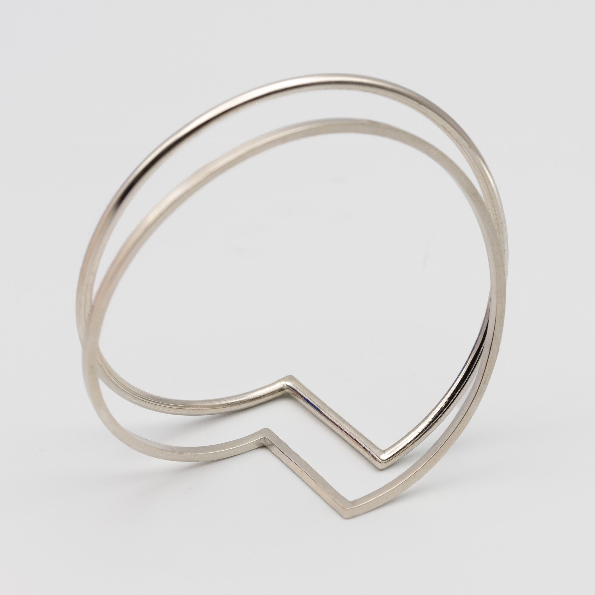 two minimalistic silver bangles one made out of square wire the other out of round wire